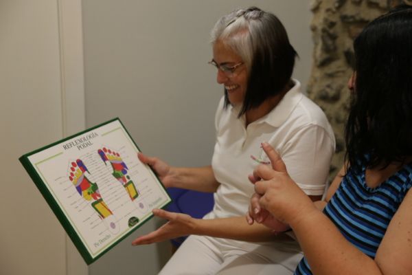 Viviana Althaus terapeuta enseñando un foto sobre reflexología podal a una clienta en Sant Celoni